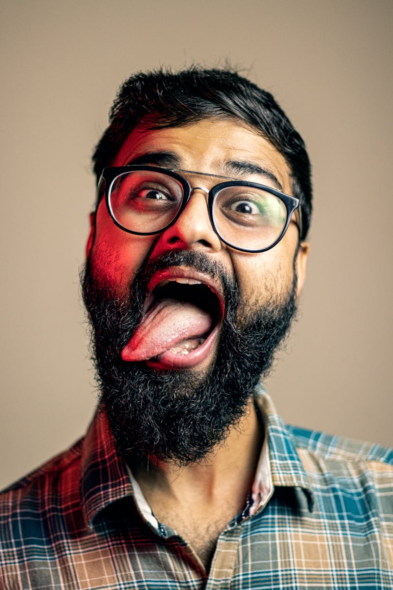 Close-up portrait of a bearded man making a funny face with glasses.