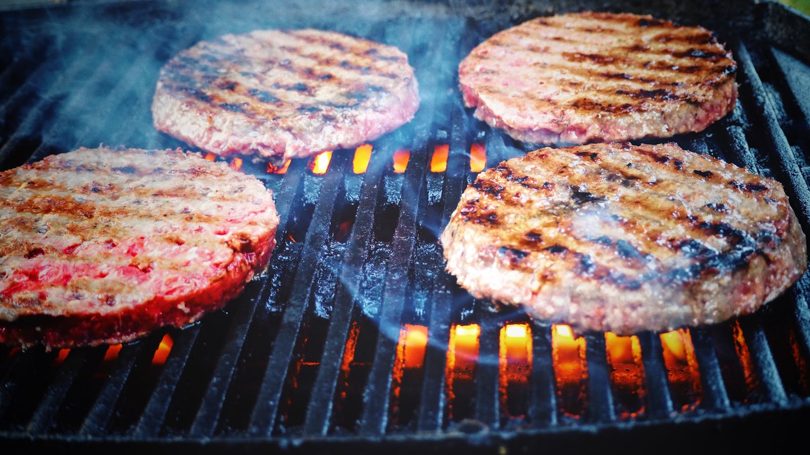 Filosofando sobre o hambúrguer Juicy beef patties cooking on a hot grill, perfect for barbecue cookouts.